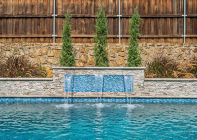 a raised wall in a pool with sheer descents cascading into the water
